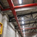 Red de rociadores y equipos de protección contra incendios instalados en nave industrial con tuberías rojas y extintores